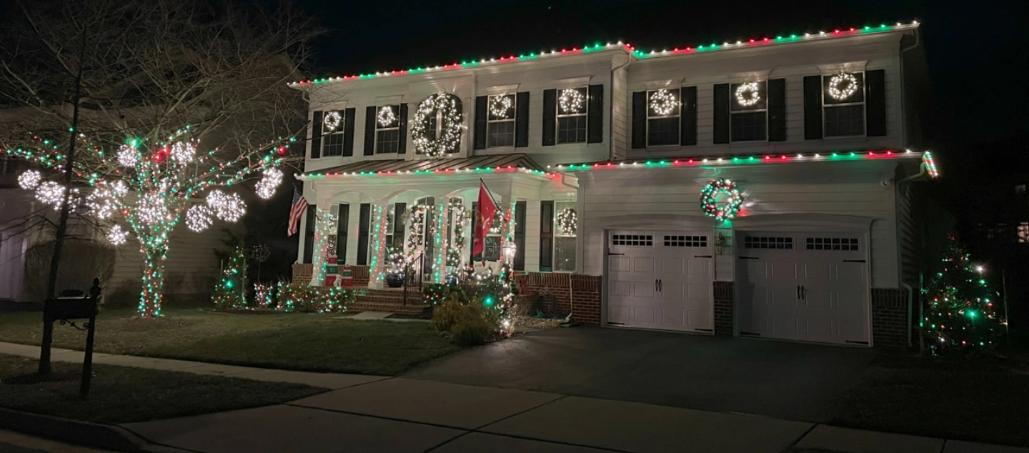 Large single-family home lit up by white holiday lights.