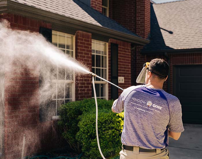 Window Genie tech pressure washing a brick home during a commercial house washing appointment