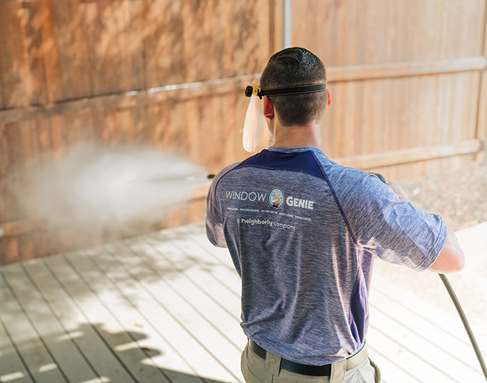 Window Genie technician pressure washing a wood fence