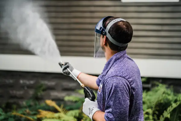 Tech performing pressure washing at a commercial establishment.