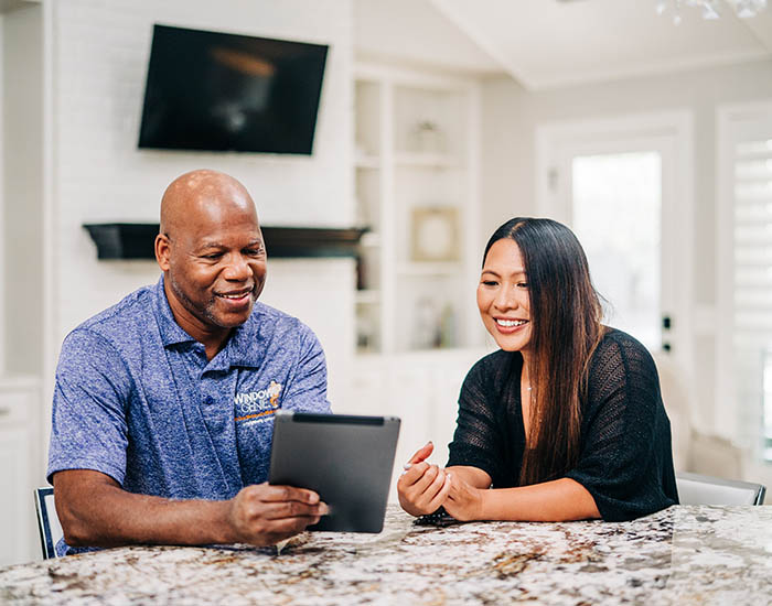 Window Genie tech and a customer at a table reviewing window cleaning service details 