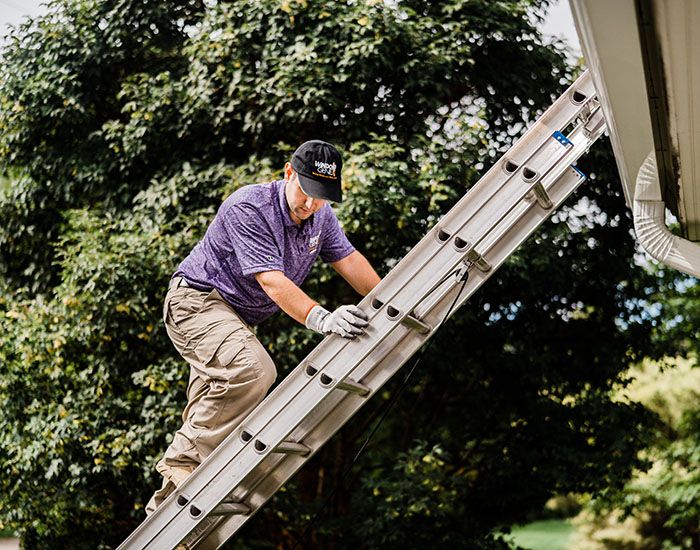 Window Genie tech climbing down a ladder after completing solar panel cleaning on a home 