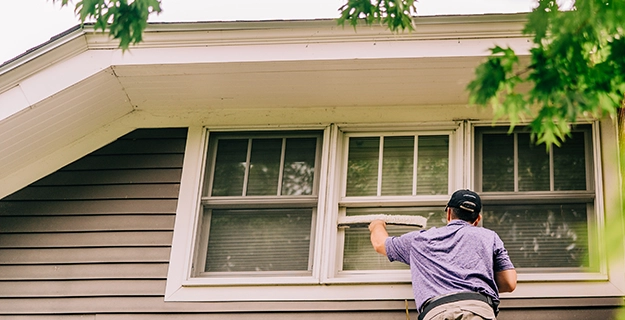 Window Genie professional cleaning a window on the outside of a home.