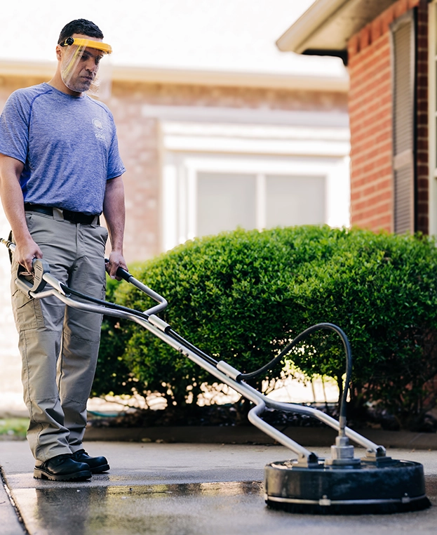 Window Genie service professional using a professional-grade pressure washer to clean a stone patio.