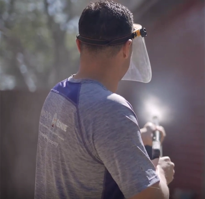 Window Genie service professional power washing the siding of a house.