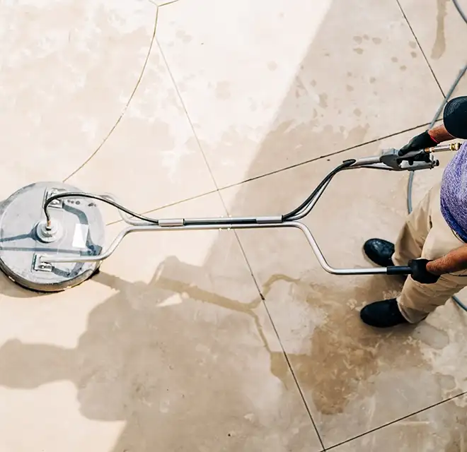 Window Genie service professional using a professional-grade pressure washer to clean stone patio.
