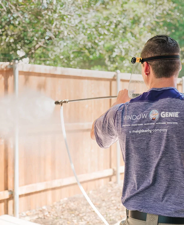 Window Genie service professional pressure washing a deck.