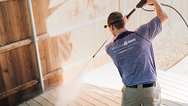 Window Genie technician pressure washing a wood fence.