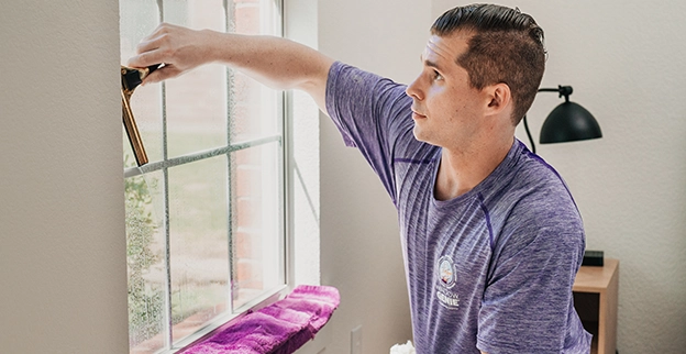 View from inside a building of a man cleaning the outside of a window.