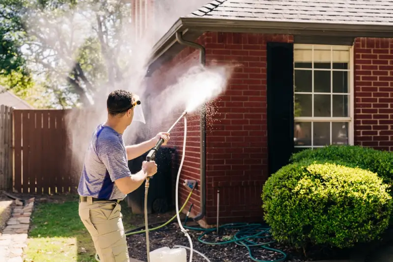 Window Genie professional pressure washing a brick house.