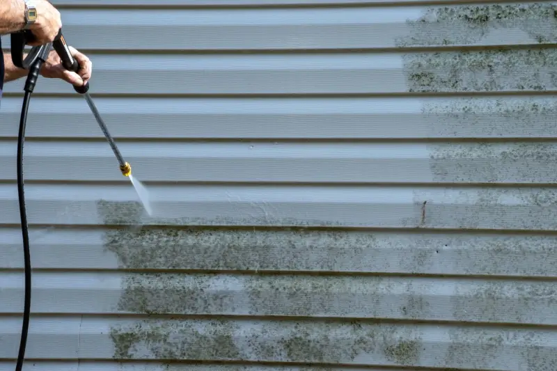 Dirty house siding being pressure washed.