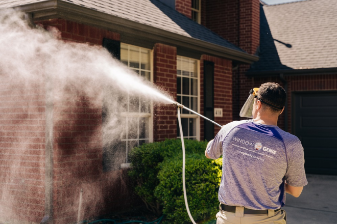 Window Genie professional pressure washing a brick house.