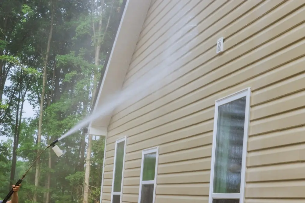 Pressure washing exterior of a home.