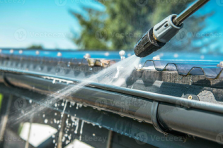 Close-up of a pressure washer cleaning a house gutter.